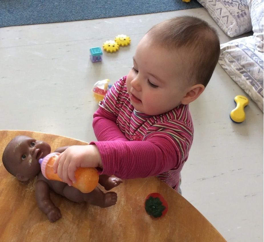 A baby exploring responsive doll play at A.C.E
