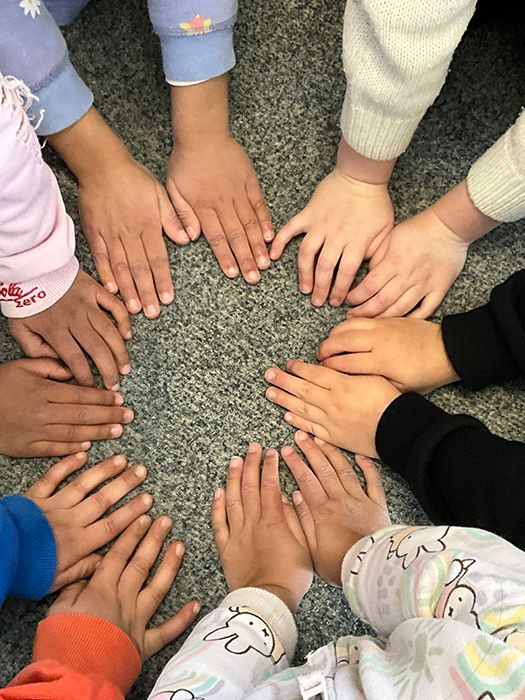 Children’s hands gathered in a circle at A.C.E