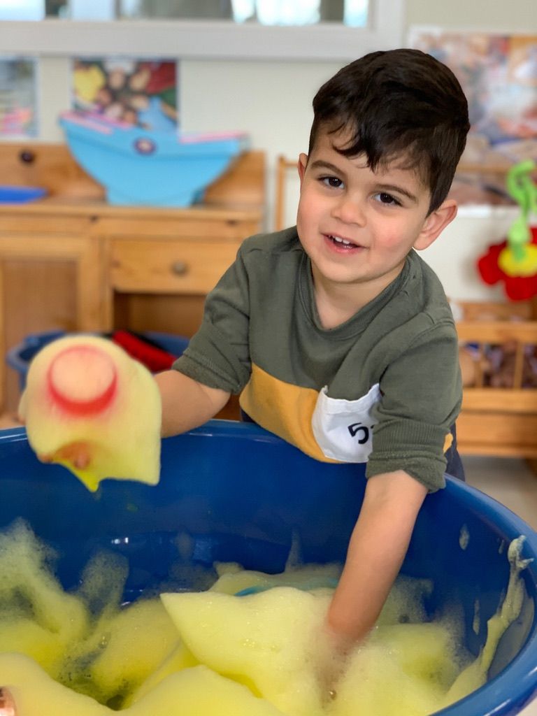 A toddler exploring water and sensory play at A.C.E