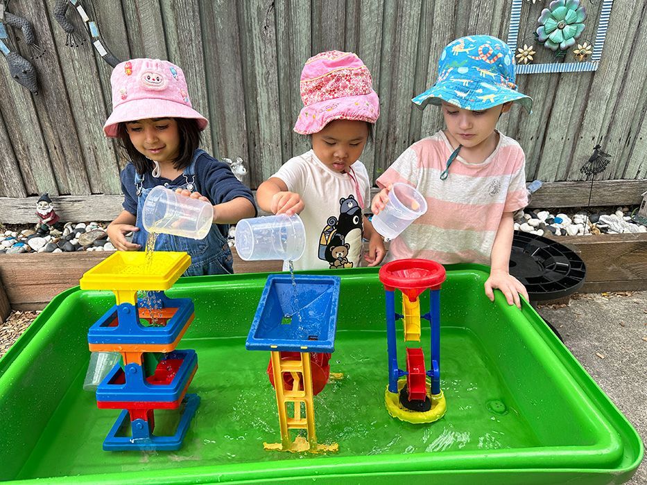Children collaborating at an outdoor water table